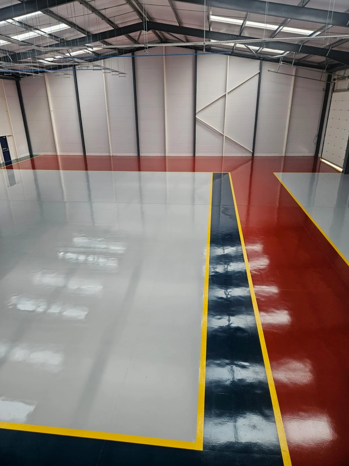 CEJN Hereford industrial floor with grey, red and dark coated zones separated by yellow demarcation lines