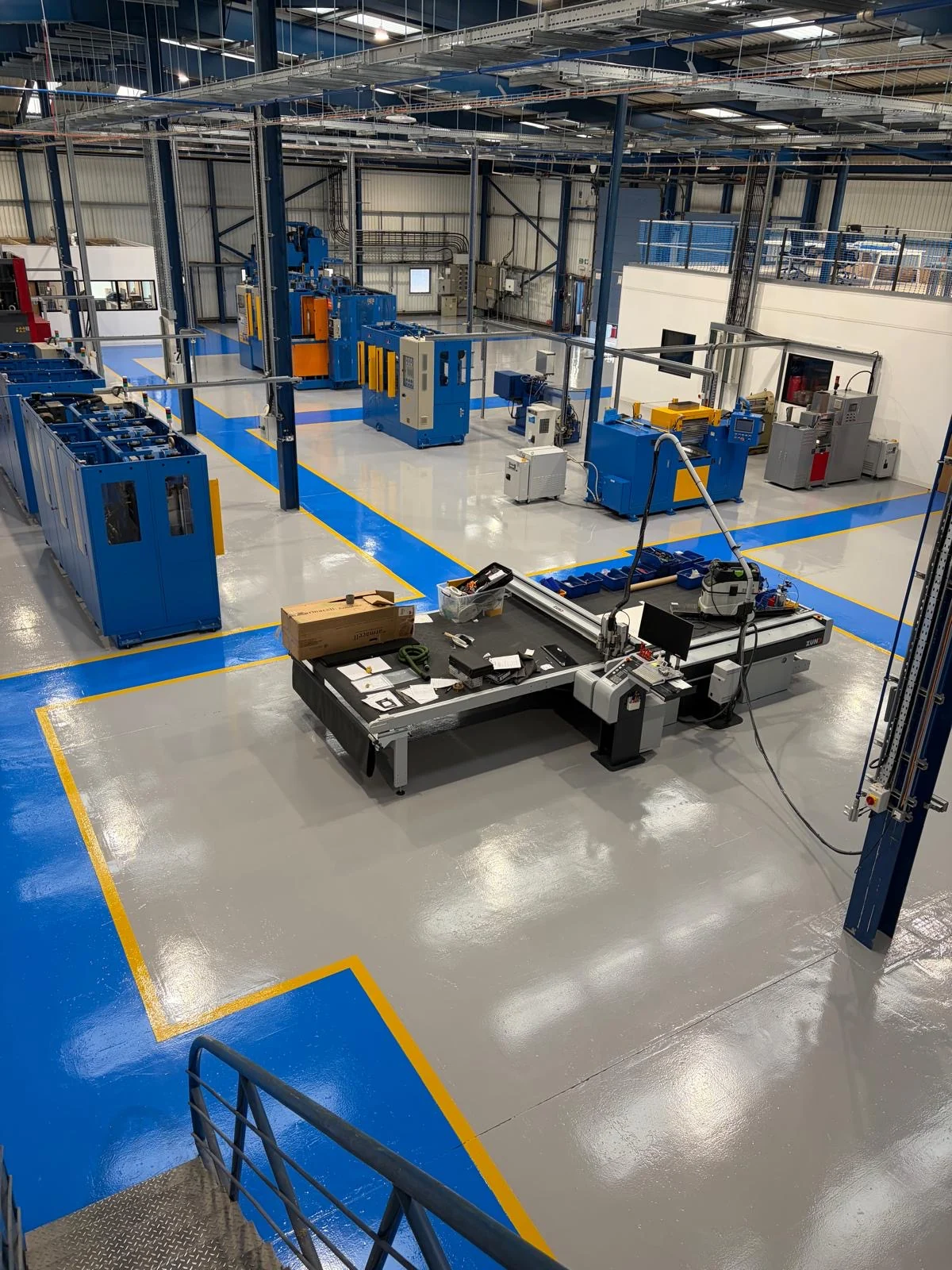 SB Rubber Havant factory with a grey coated floor, blue marked routes and yellow boundary lines around manufacturing equipment